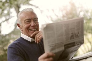Un senior souriant avec un journal à la main.
